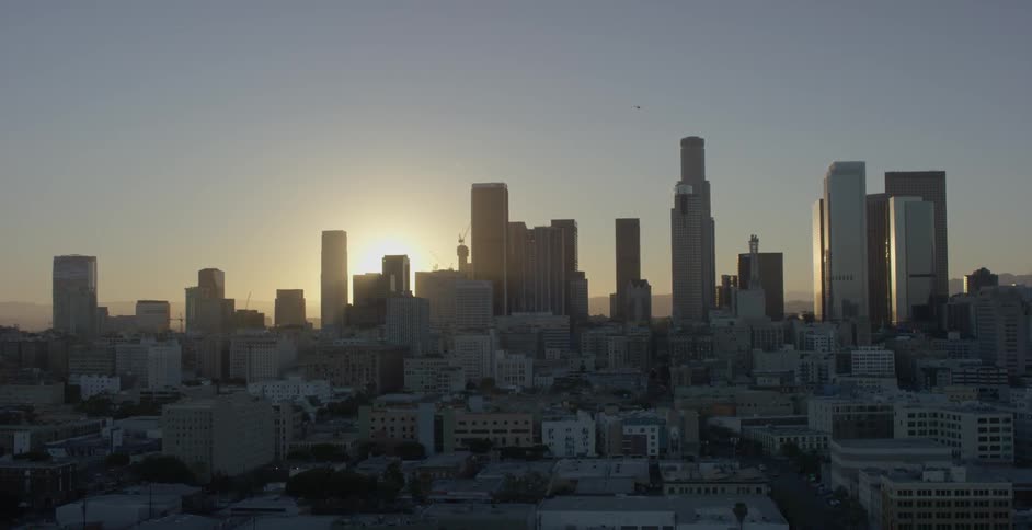 The sun sets behind city skyscrapers