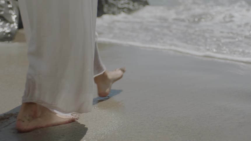 A person is walking across the sand
