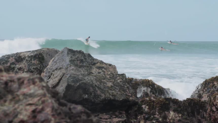 A surfer rides a wave towards the shore