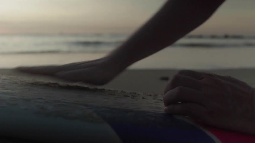 A surfer rubs their surfboard
