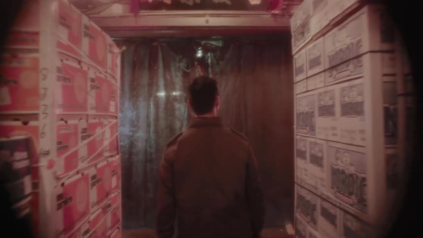 A man walks through a warehouse with stacked boxes