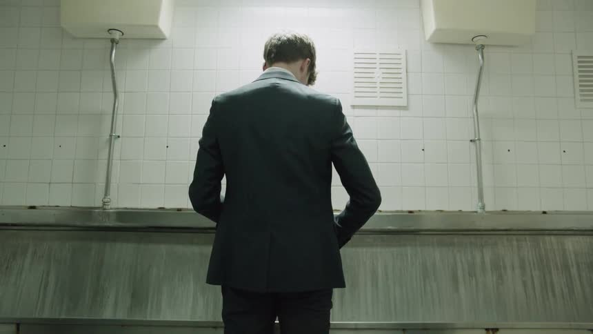 A man walks up to a bathroom urinal