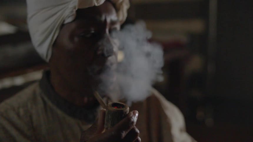 Person lighting and smoking a pipe in a dark area
