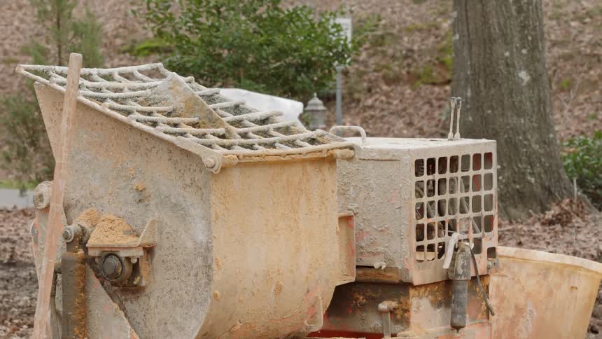 A mortar mixer sits in a yard