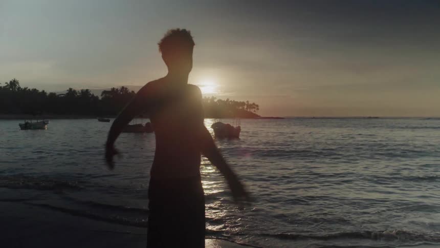 Man puts a surfboard down and waves his arms