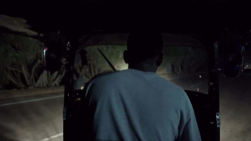 A man drives a small vehicle on a road at night
