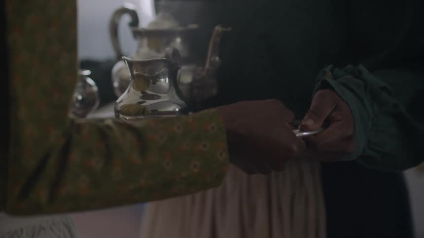 A woman hands a serving tray to another woman