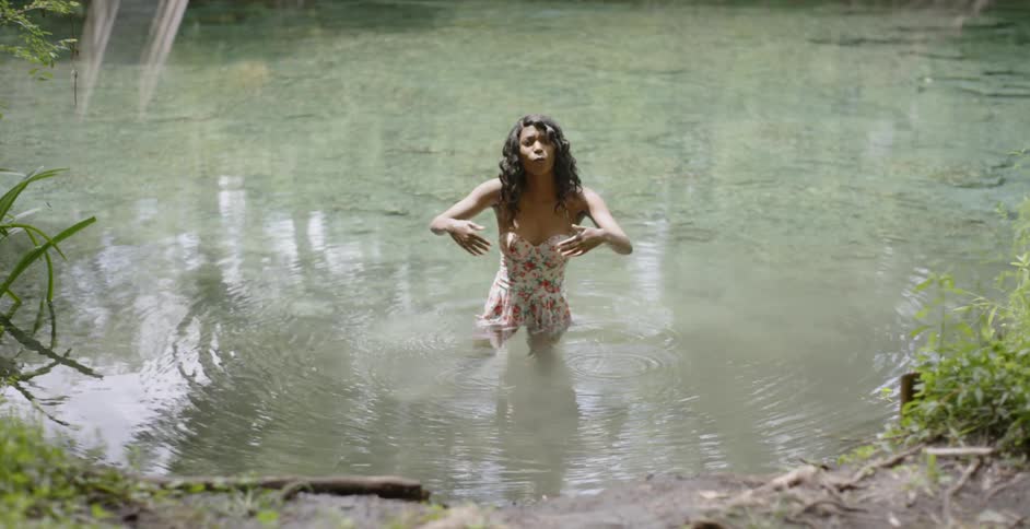 Woman wading in a lake motioning her arms