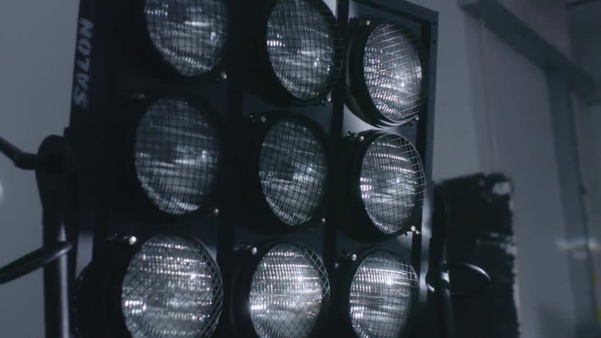A light is skimming across a bank of portable lights indoors