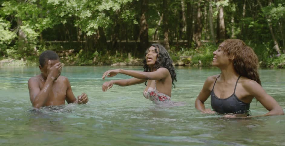 A woman splashes a boy while swimming in a lake
