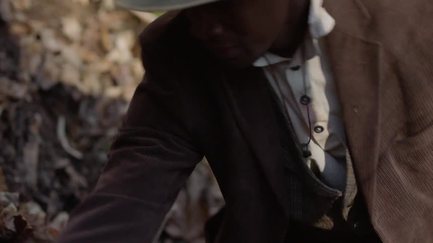 A man is digging through the leaves searching for something