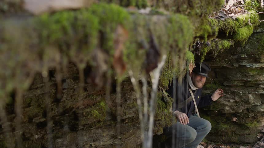 A soldier takes cover under a rock ledge