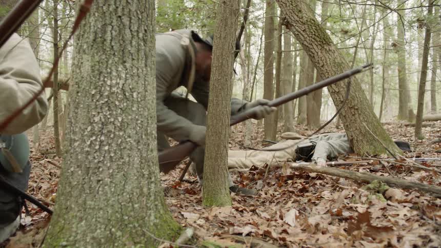 A soldier reloads his rifle in the woods