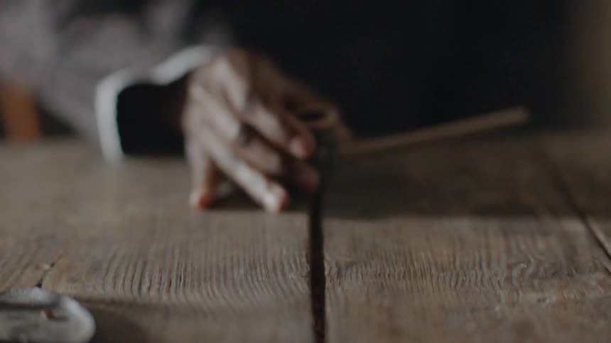 Hand picks up a pipe off a wooden table