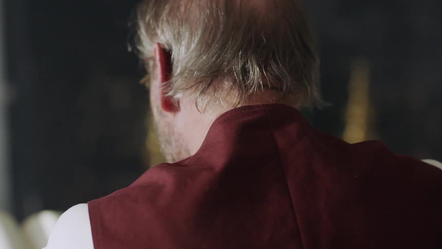 A man wearing glasses looks down at something