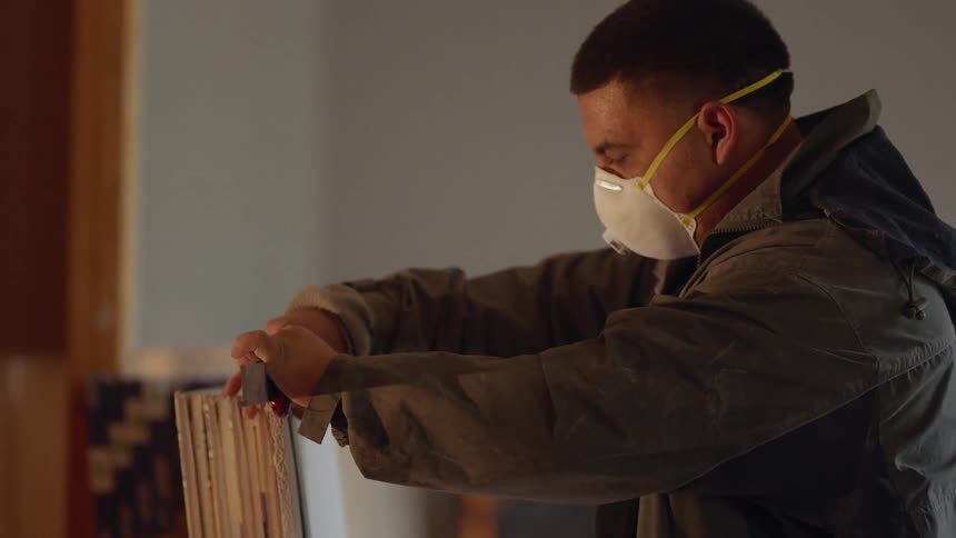 Man wearing a mask cuts into drywall