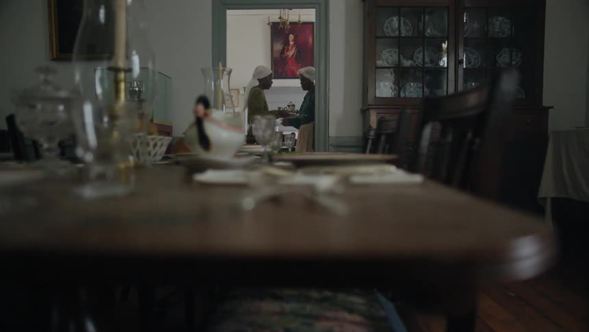 Two women work as servants inside a house