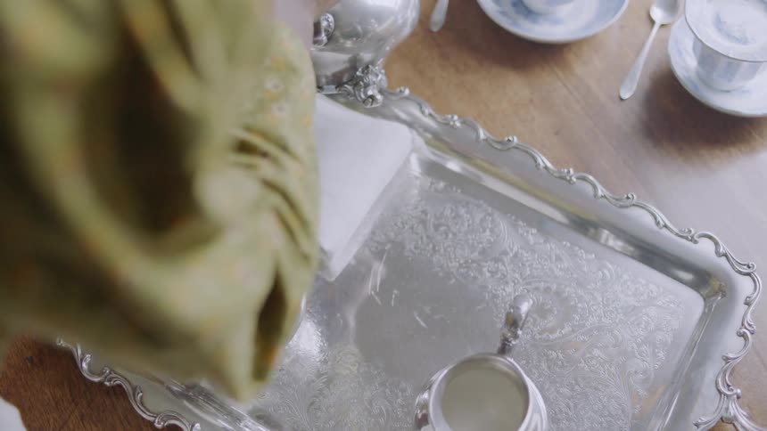 A woman serves tea at a table