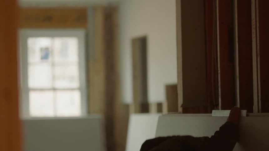 A construction worker takes measurements in a room