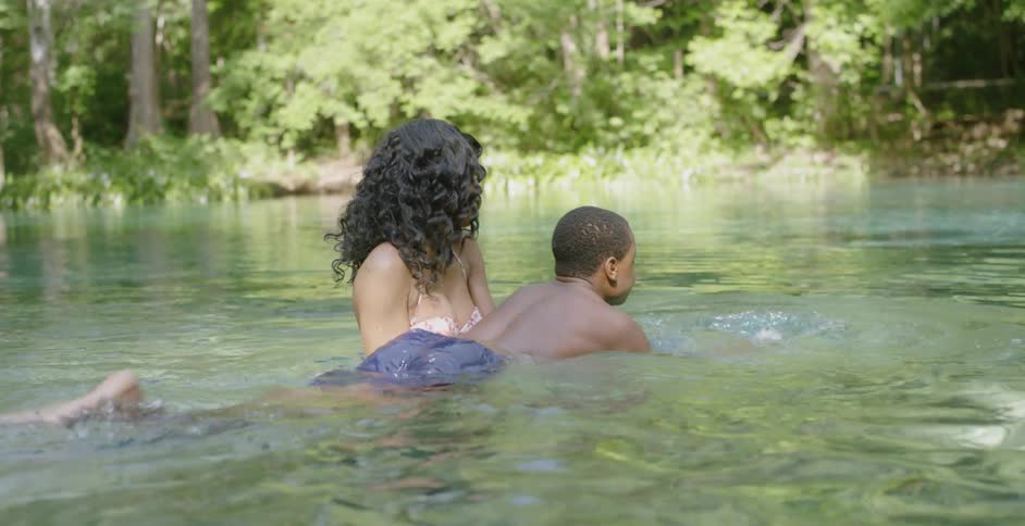 Woman holds a boy in a pond, teaching him how to swim