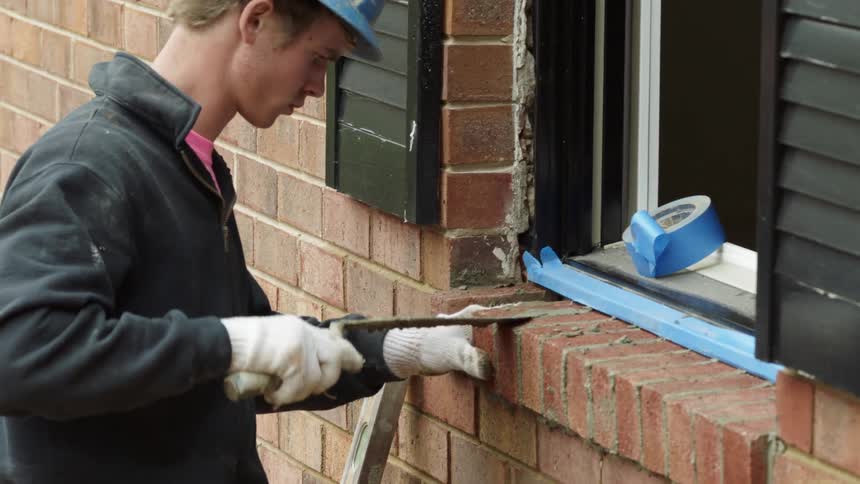 A man muds brick on a window sill