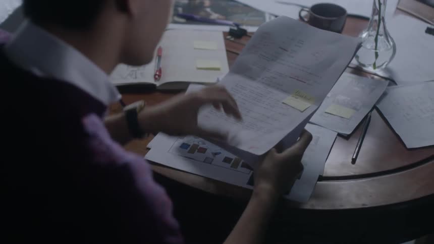 A man is going through paperwork inside at a table