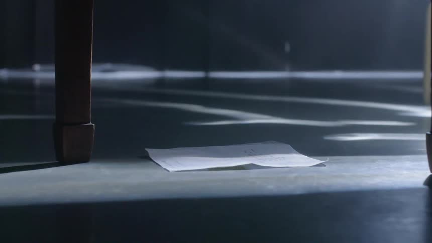 A piece of paper falls on the dark floor