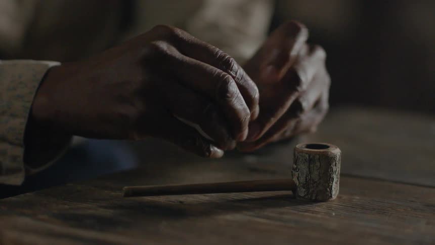 A man is putting together a pipe inside at a table in daylight