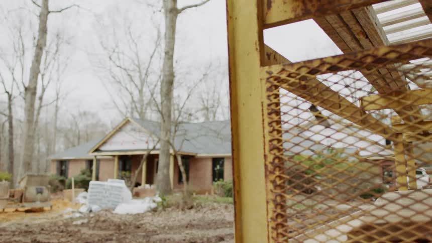 Construction equipment is set up outside of a brick house
