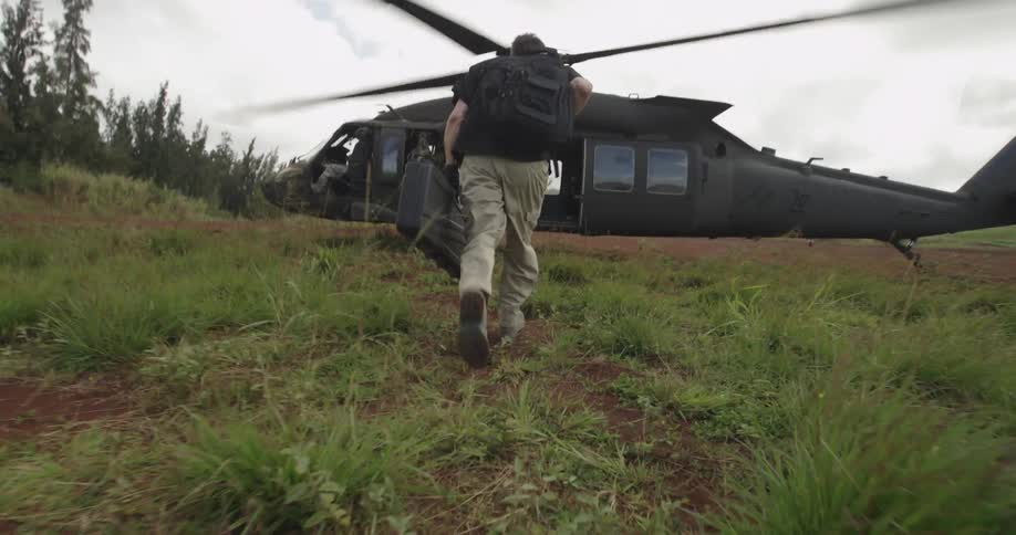 A man carries his rifle toward his copter
