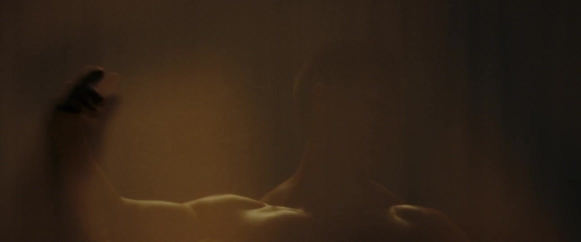 A man raises his hands and moves them around in the foggy room