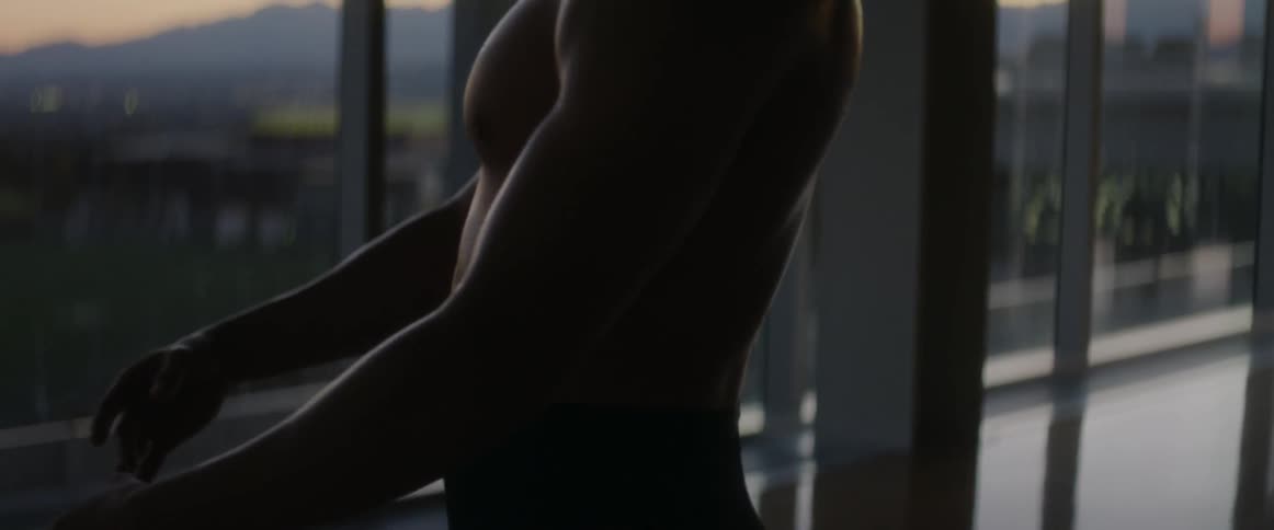 A man prances inside a room with many windows