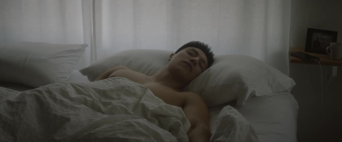 A man is sleeping in his bed early in the morning