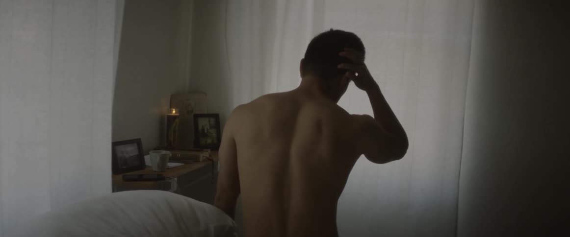 A man sitting on his bed rubs his head