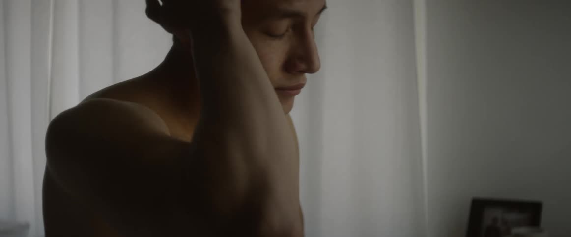 A man sits on the edge of a bed