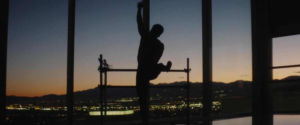 Man does ballet in a dance studio at dusk