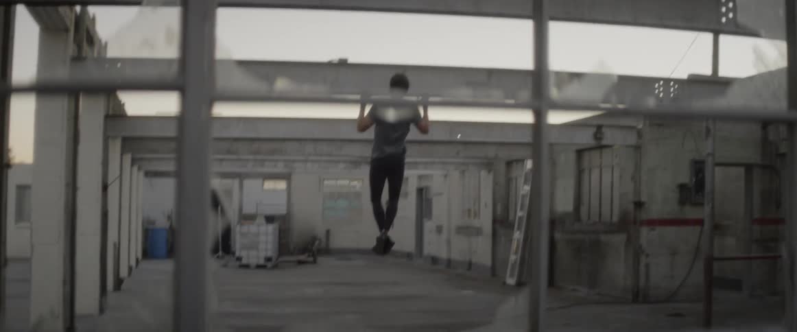 Man does pull ups on a metal rafter