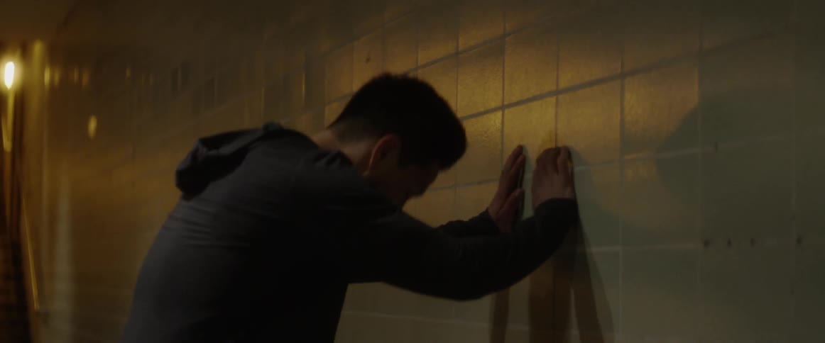 Man leans against a tile wall