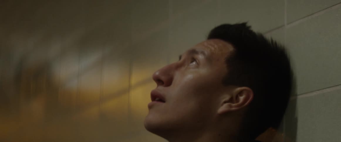 A man is looking up leaning against tiles