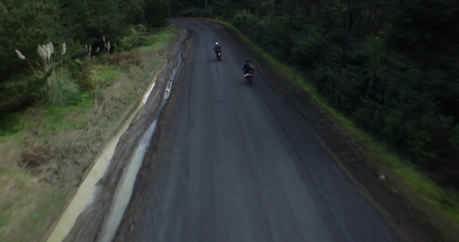 Two motorcycles travel quickly down a road