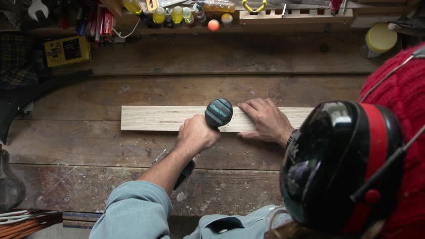 Man drills a hole in a wooden board
