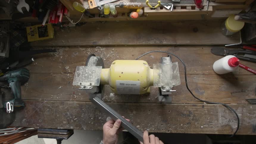 Man grinding a metal bar on a machine