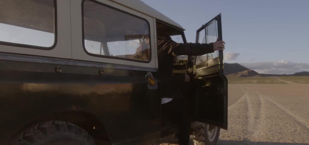 Man climbs into a vehicle while traveling near mountains