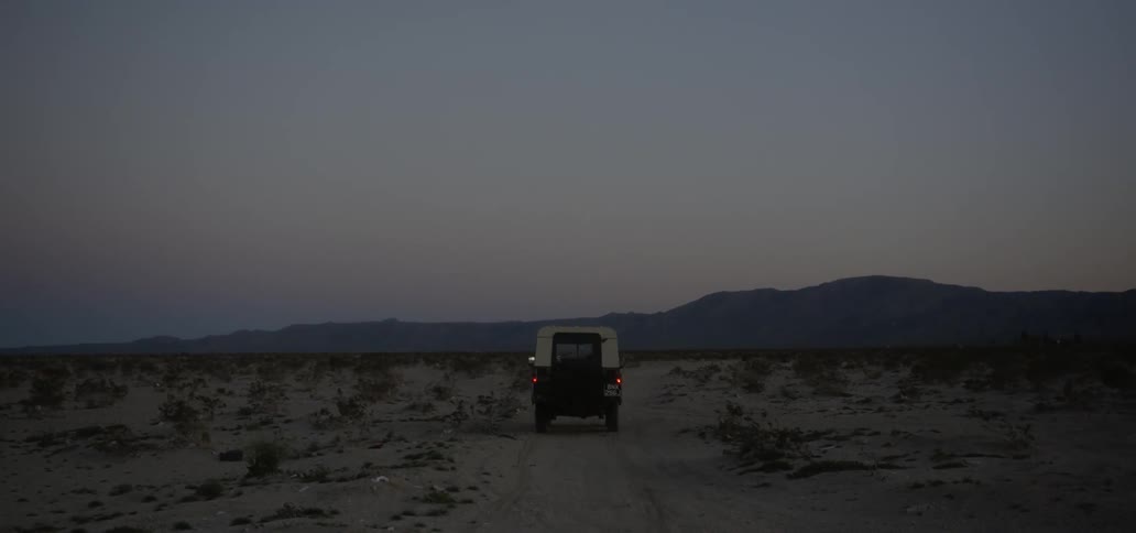 Jeep driving through sandy wilderness after sunset