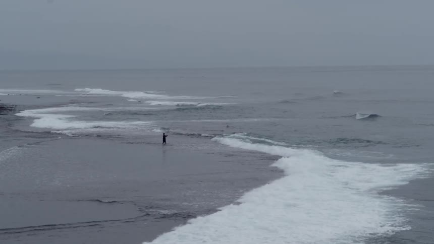 Person fishes on a beach