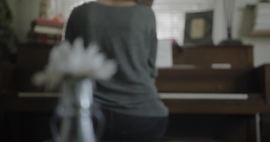 A woman sits and plays a piano