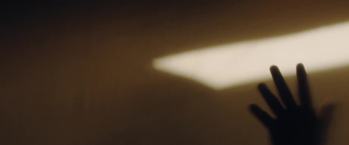 A man stretches his arm and reaches up in hazy light