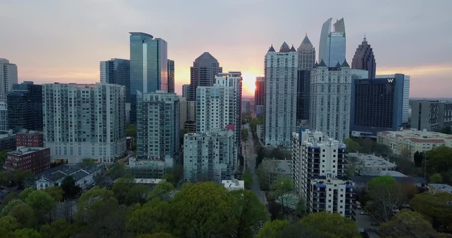 The sun sets behind skyscrapers