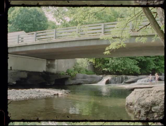 Water flows down a stream under a bridge
