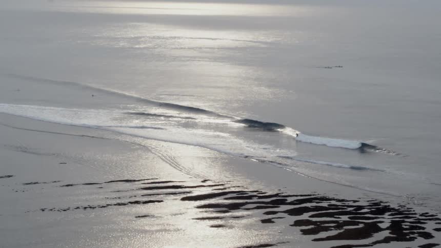 A surfer rides a wave to shore